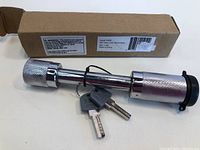 Barrel style hitch lock with keys and original box visible in background.