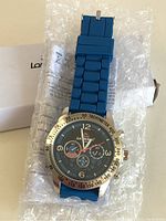 Longboard men's wristwatch with blue silicone band, displayed on bubble wrap, showing face details and bezel tachymeter scale.