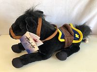 Side profile of black RCMP horse plush showing saddle, bridle, and tag attached to ear.