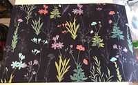 Top side of rectangular rubber mat with colorful floral print on black background