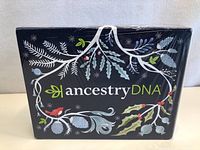 Front view of the sealed AncestryDNA activation kit box featuring decorative botanical design and branding.