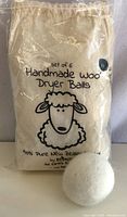 Set of 6 wool dryer balls in a cotton drawstring bag with branding and product info.