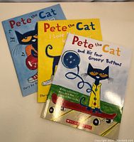 Photo of three new Pete the Cat children's books laid out on a flat surface. Each book has a glossy cover with the Pete the Cat character depicted in different scenarios and bright colors.
