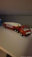 Side view of the vintage red Tonka fire truck showing the extendable white ladder and six wheels.