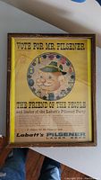Front view of framed vintage Labatt's Pilsener advertising poster titled 'Vote for Mr. Pilsener' with yellow background and cartoon character.