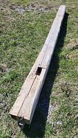 Full length of the barn beam displaying its length, texture, square cut-out, and attached metal hardware.