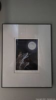 Framed indigenous art print with visible full moon and three wolves howling beneath it. Artwork is signed and titled on the bottom margin.