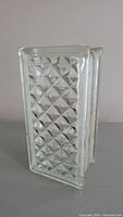 Front and side view of the clear glass brick showing diamond texture on surface and hollow center.