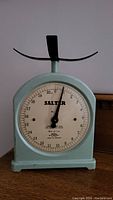 Front view of the green iron Salter kitchen scale showing white dial with black numbering and needle at zero position.