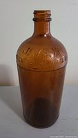 Front view of amber glass Javex bottle with embossed text and no cap