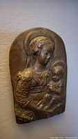 Front view of bronze relief plaque showing Madonna holding child Jesus with halos.