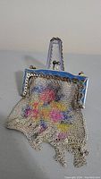 Front view of the vintage metal mesh chain change purse showing the blue enamel scalloped frame and floral pattern on the mesh body.