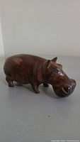 Front and left side view of wooden hippopotamus figurine showing round head and short legs.