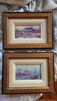 Front view of two framed prints showing different scenic artworks with carved wooden frames and light matting.