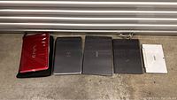 Five laptops lined up on floor, showing variety of brands and colors including VAIO, Dell, Acer, and ASUS.