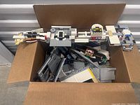 Top down photo showing large cardboard box with scattered Star Wars LEGO pieces, including a large partially constructed main structure in the box.