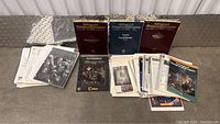 Advanced Dungeons & Dragons 2nd Edition Barbarian's Handbook, Player's Equipment, The Complete Priest's Handbook hardcover books plus scattered loose sheets and printed materials.