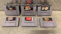 Top view of six SNES game cartridges showing front labels including Street Fighter II Turbo, ClayFighter, Naruto, Donkey Kong Country, Final Fantasy III, and another game.