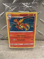 Photo shows a sealed Special Delivery Charizard Pokémon card featuring Charizard with Pikachu and text of the card including HP 160 and moves Happy Delivery and Flamethrower.