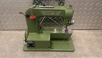 Side view of green Elna sewing machine showing brand name and manual crank