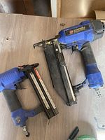 Photo of two Campbell Hausfeld brad nailers on a wooden surface, showing overall used condition