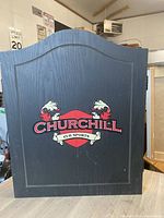 Closed black wooden cabinet with Churchill Pub Sports logo on front.