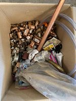 Box containing copper tubes, elbows, fittings, clamps, flexible tubing and plumbing tools.