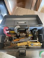 Open gray toolbox filled with various handyman tools including pipe cutters, saw, wrench, and air gun