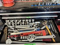 Drawer of assorted large wrenches, pipe wrenches, adjustable wrenches, sockets, hammer, and screwdriver.
