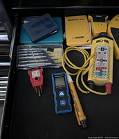 Photo of the lot showing various electrical testers and accessories such as a Vol-Con device, Mastercraft tester, probe tips, and manuals arranged inside a drawer.