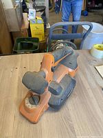 Full view of the orange and black cordless planer on a wooden table showing dust and wear.