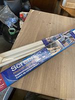 Original packaged replacement screen frame box on a brown table with black chair in background.