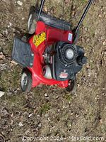 Red Yard Machines gas-powered push lawnmower on grass with visible engine and handlebar.
