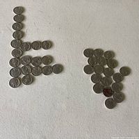 37 Buffalo nickels arranged in two groups on white surface showing obverse side. Various wear visible on coins.