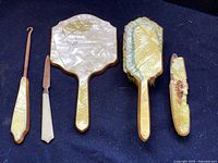 Full layout of 5 piece vanity set including mirror, brush, boot hook, nail buffer, and nail file, showing condition and material.