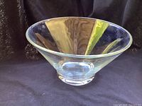 Clear vintage crystal bowl placed on dark backdrop showing flared shape, wide mouth, thick solid base.