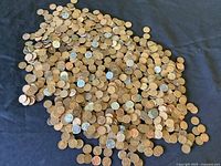 Large scattered pile of mixed copper and silver-toned pennies on black cloth