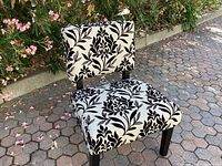 Side angle view of the black and white patterned accent chair showing seat, backrest, and legs.