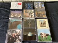 Full collection of 13 Pink Floyd CDs arranged in a grid on a dark surface, showing album covers including The Wall, Animals, Dark Side Of The Moon, and others.