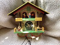 Front view of vintage wooden cuckoo clock showing chalet design and figurines