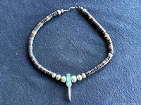 Full view of necklace laid flat on dark background showing entire length and design.