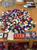 Wide view of poker chips spread on wooden table along with decks of playing cards and instruction pamphlets or rules