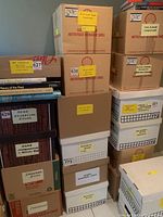 Photo showing stacked cardboard boxes labeled as business books in both hardcover and softcover formats among other categories like gardening, home decorating, and cooking books.