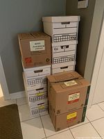 Stack of 11 cardboard boxes containing soft cover books, labeled 'Used Paperbacks'