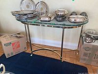 Front view of console table showing clear glass top and polished brass frame