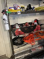 Full view of metal shelving unit holding cords, fire extinguishers, hoses, and boxes