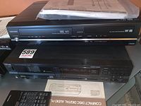 Front and top view of Toshiba DVD/VHS combo recorder with VHS and DVD slots, with remote and manuals on top.
