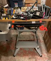 Photo showing Black & Decker Workmate 225 portable workbench with various storage hardware items placed on top, including packaged hooks and brackets.