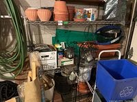 Full view of metal baker style shelf loaded with gardening items and boxes.