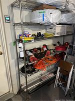Full view of the shelving unit filled with various household and utility items including extension cords, a box with spray bottles, and storage boxes on the top shelf.